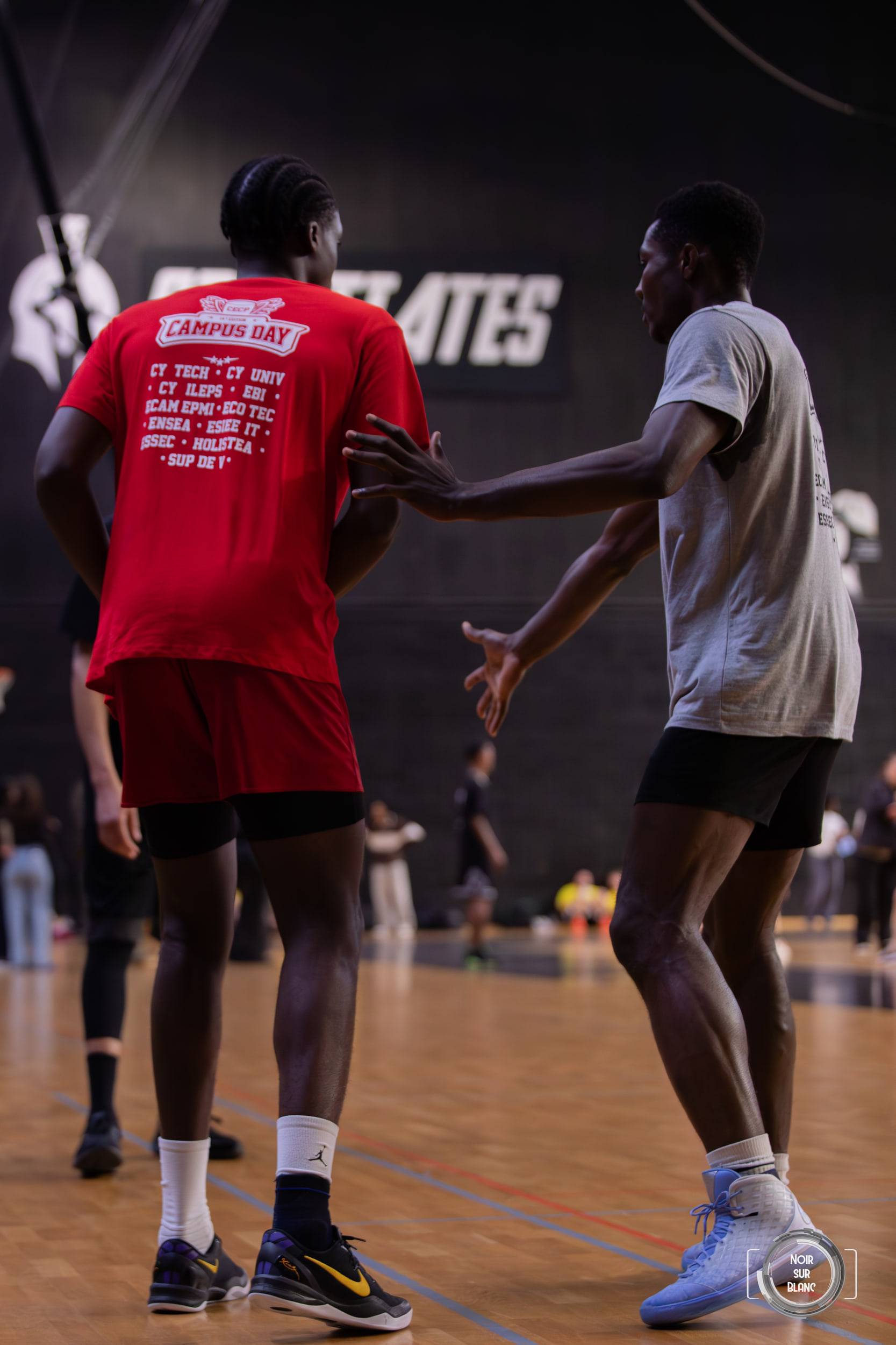 Deux joueurs, l'un en rouge et l'autre en gris, se serrent la main au milieu du terrain à la fin de la rencontre.