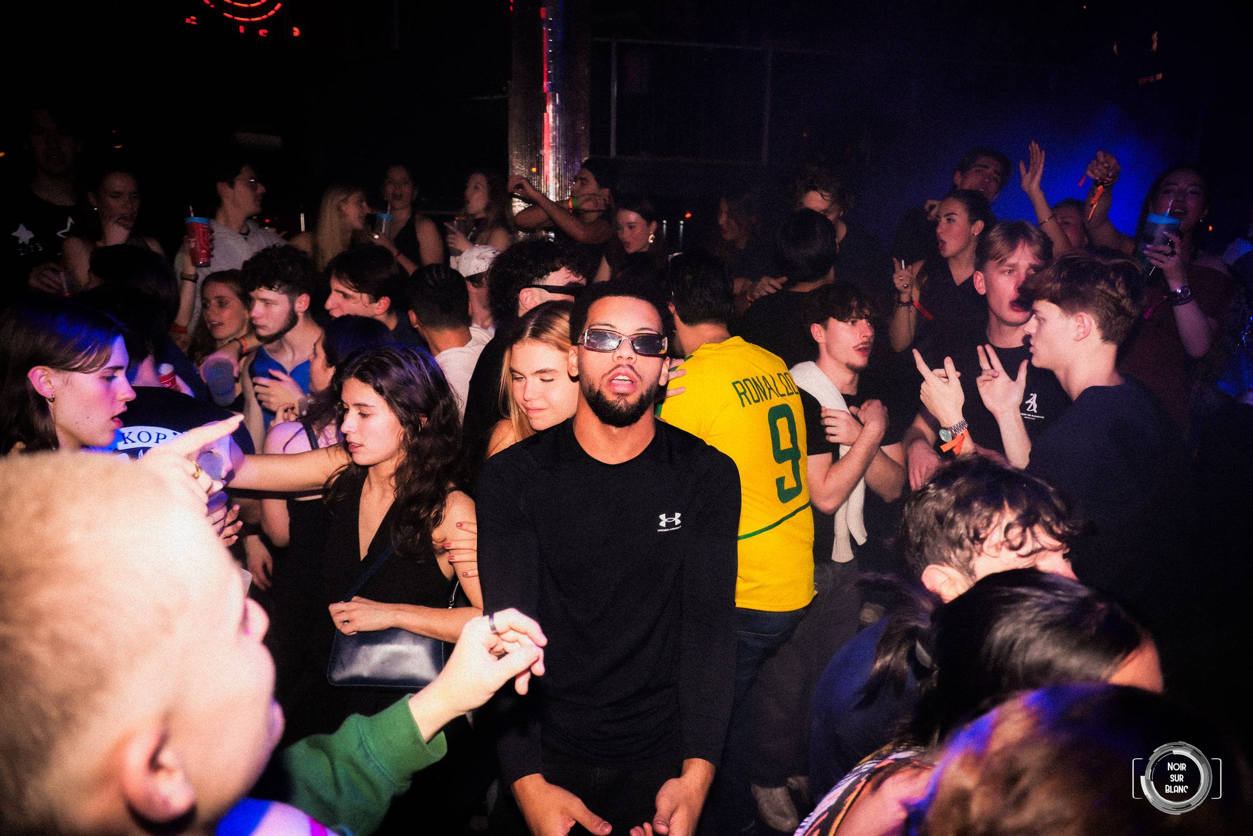 Au milieu de la foule, un étudiant en maillot de football jaune renverse la tête en arrière.