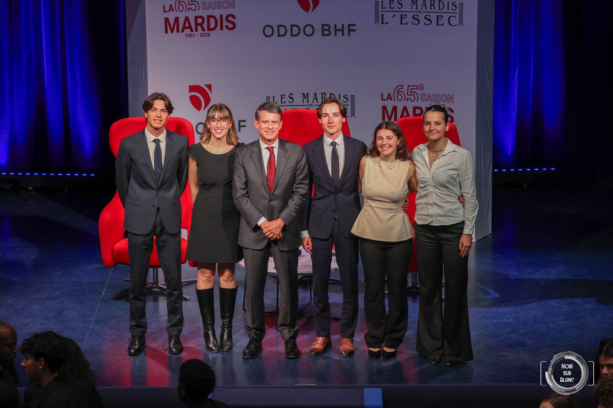 L'invité et l'équipe organisatrice alignés sur scène devant le décor des Mardis de l'ESSEC, à la fin de la soirée.