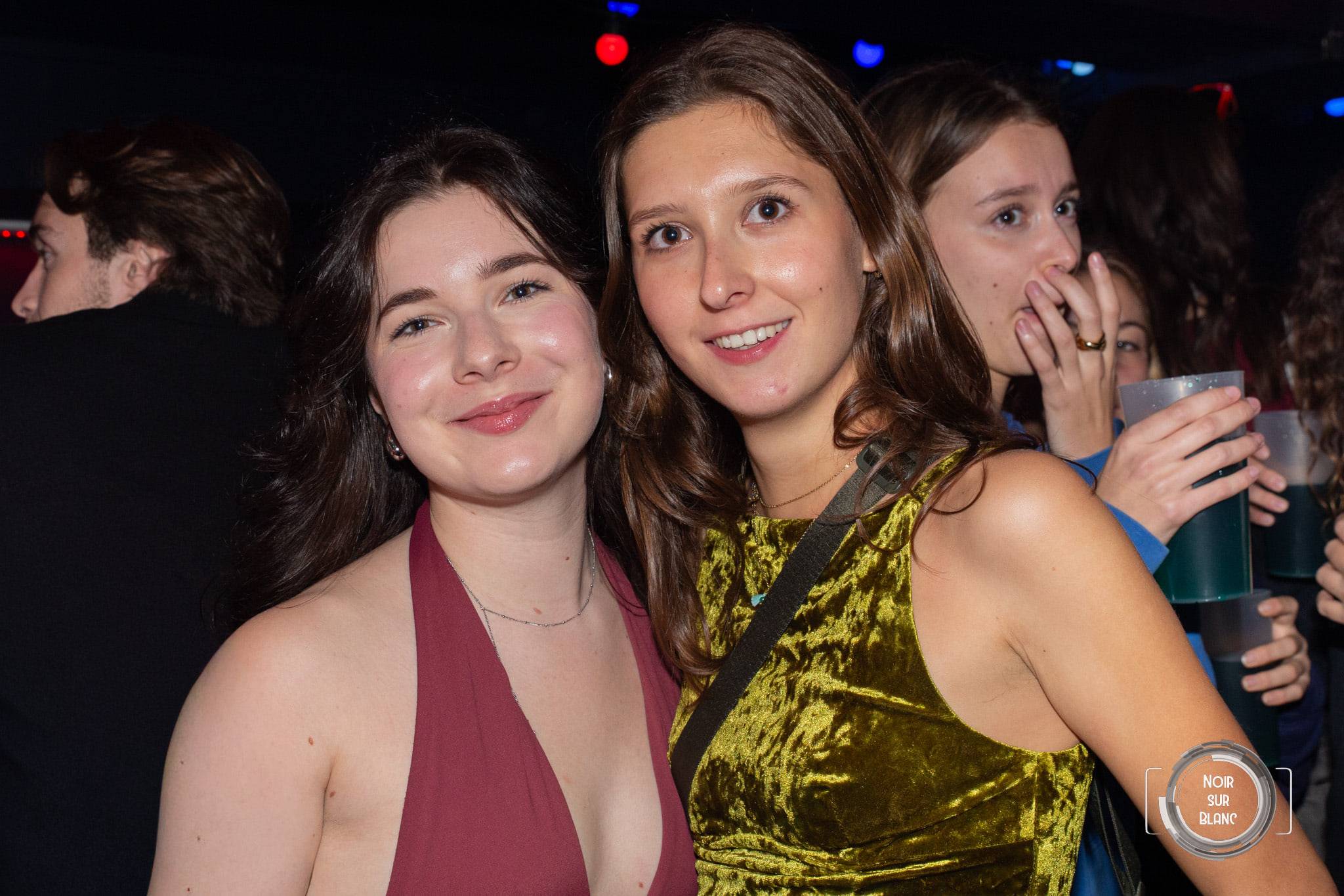 Trois jeunes femmes posent côte à côte, celle du milieu dans une robe dorée qui accroche la lumière.