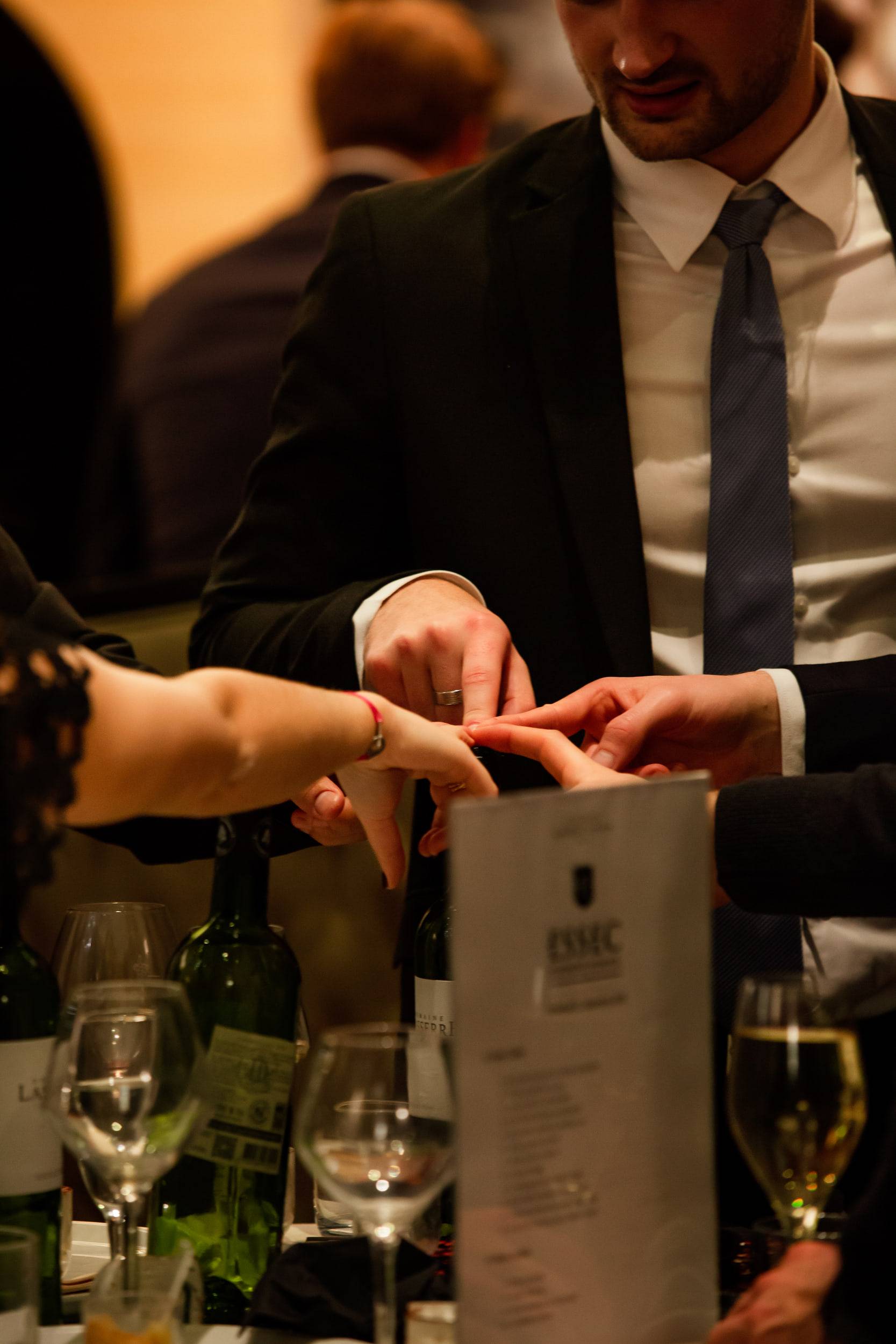 Plusieurs mains se croisent au-dessus d'une table de bouteilles et de verres pendant le service.