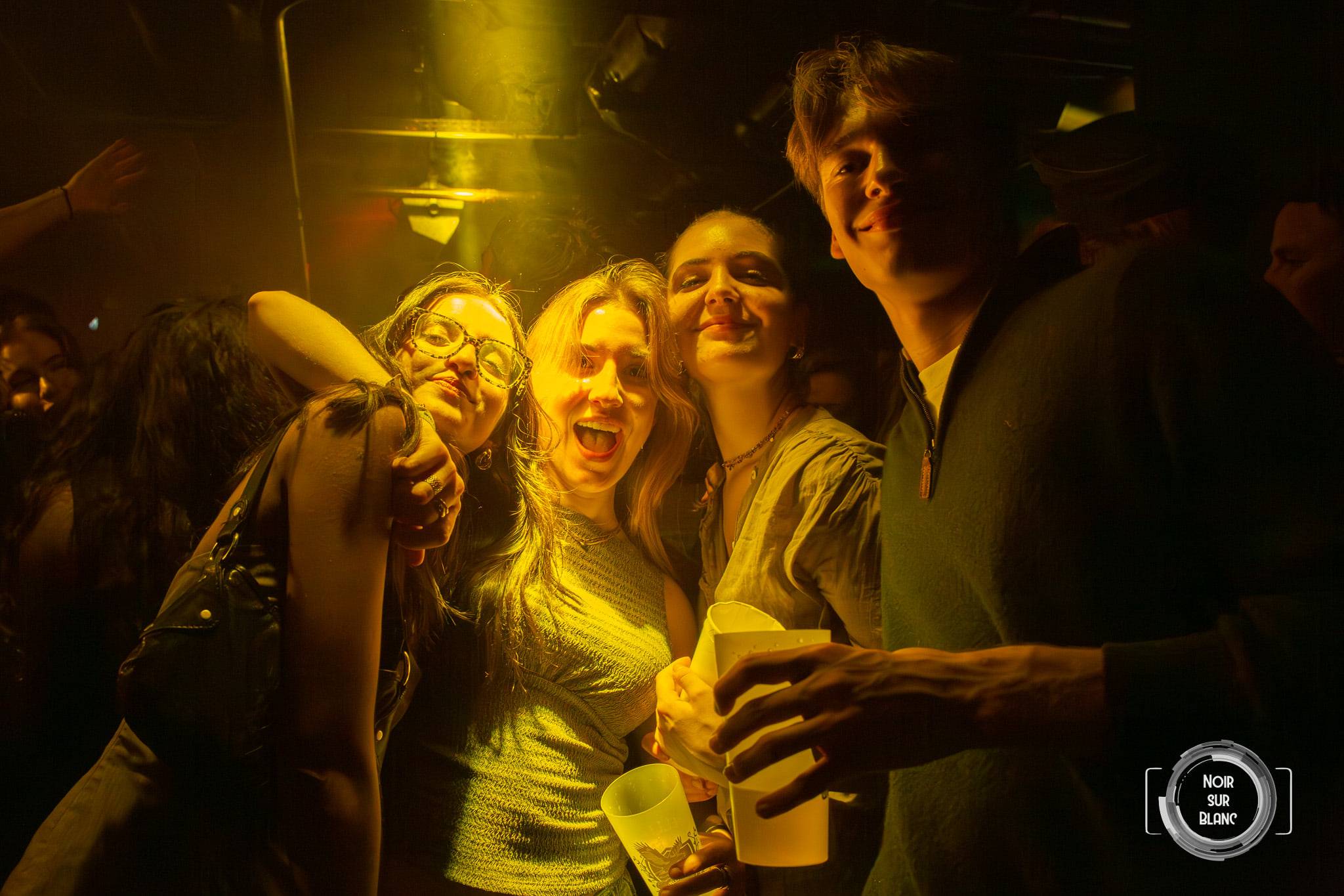 Baigné d'une lumière jaune, un groupe d'amis rit et se tient par les épaules au milieu de la piste.