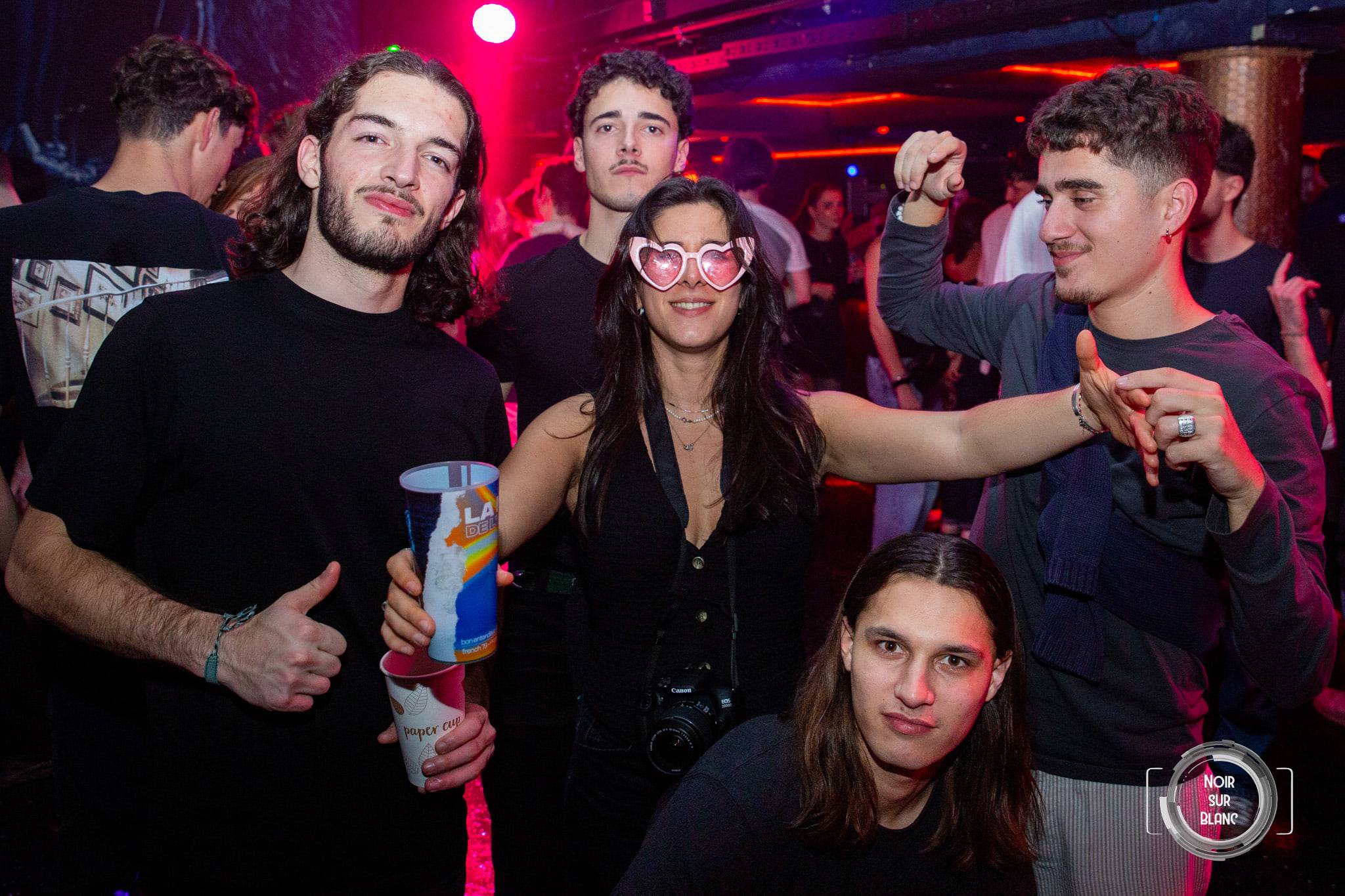 Un groupe pose face à l'objectif, l'une des fêtardes portant des lunettes roses en forme de cœur.