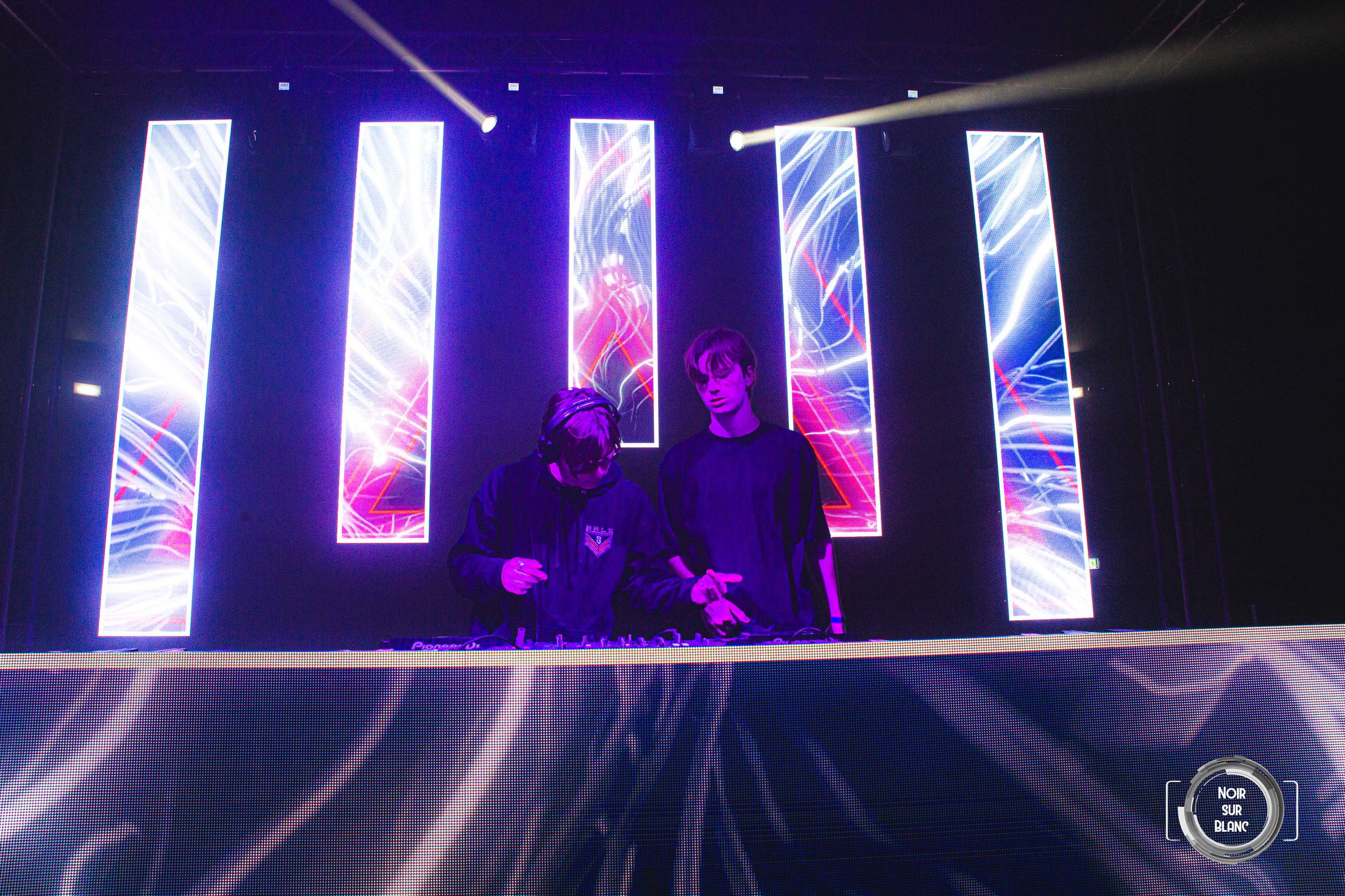 La scène et ses colonnes d'écrans lumineux, deux DJ silhouettés derrière la console.