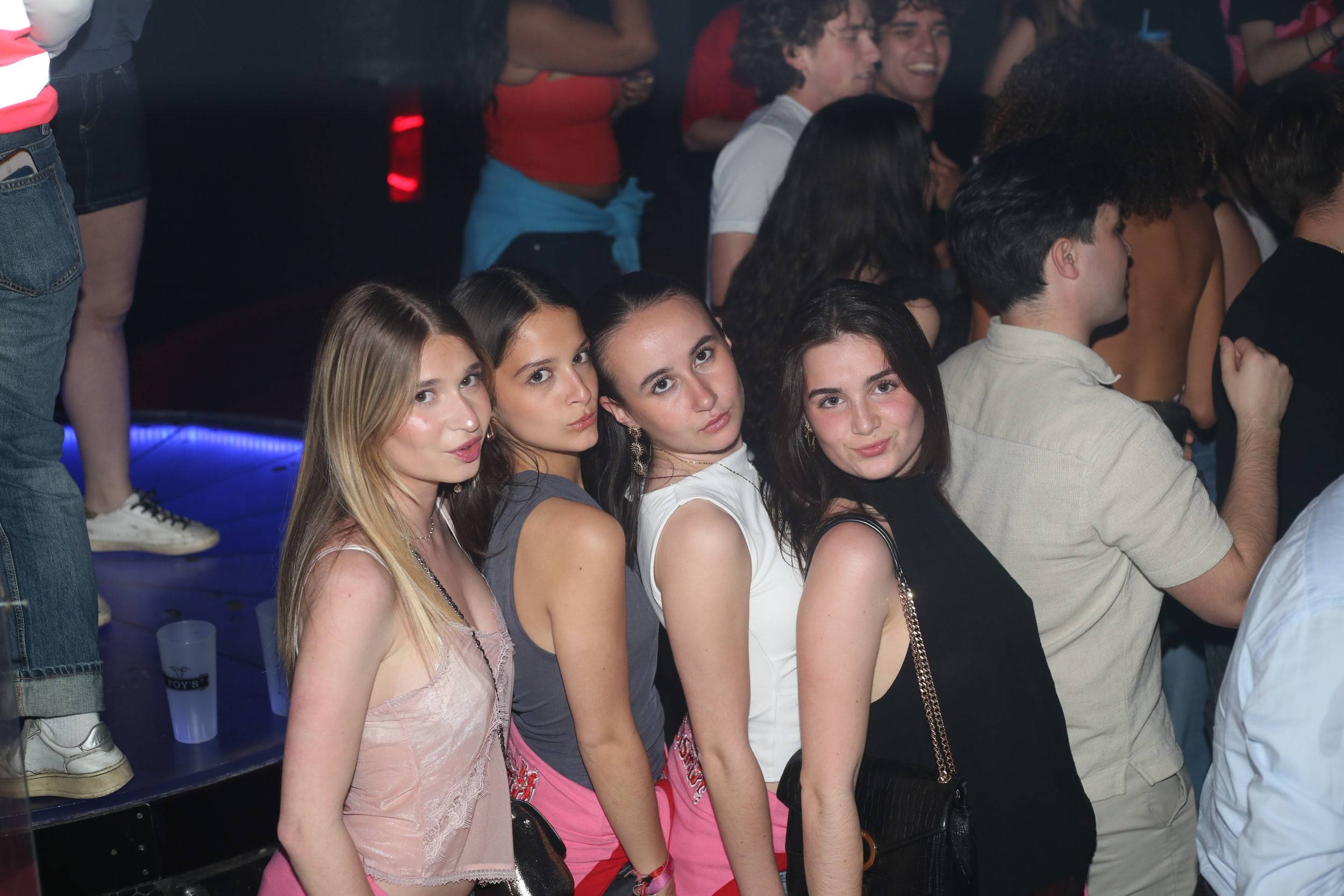 Quatre étudiantes alignées posent devant la banquette éclairée du club.