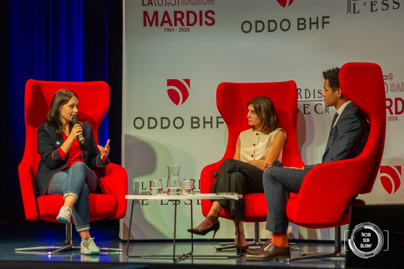 Trois intervenants assis dans des fauteuils rouges sur la scène des Mardis de l'ESSEC, l'une d'elles au micro.
