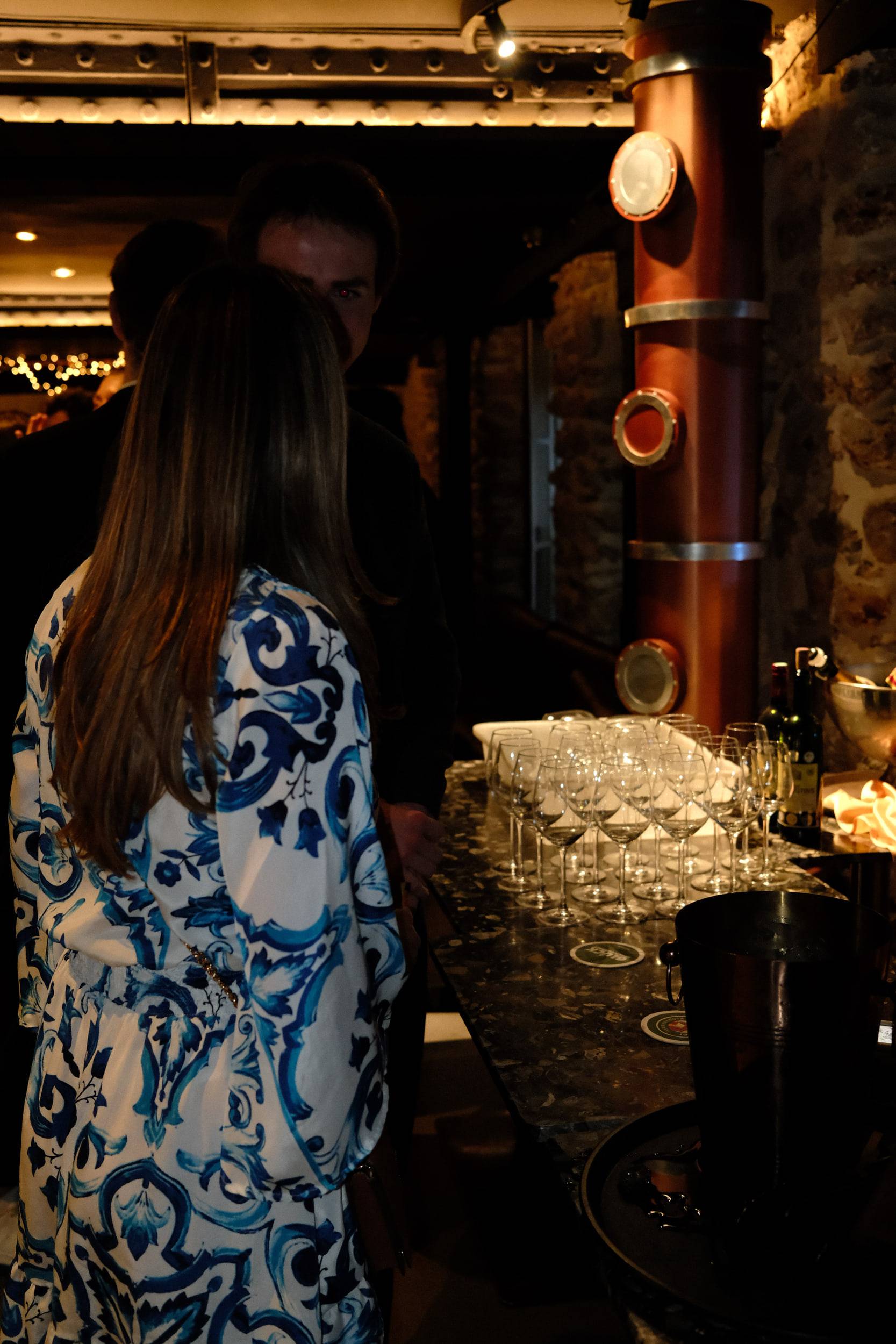 Une invitée de dos face au comptoir, où sont dressées des dizaines de coupes et un seau à champagne.