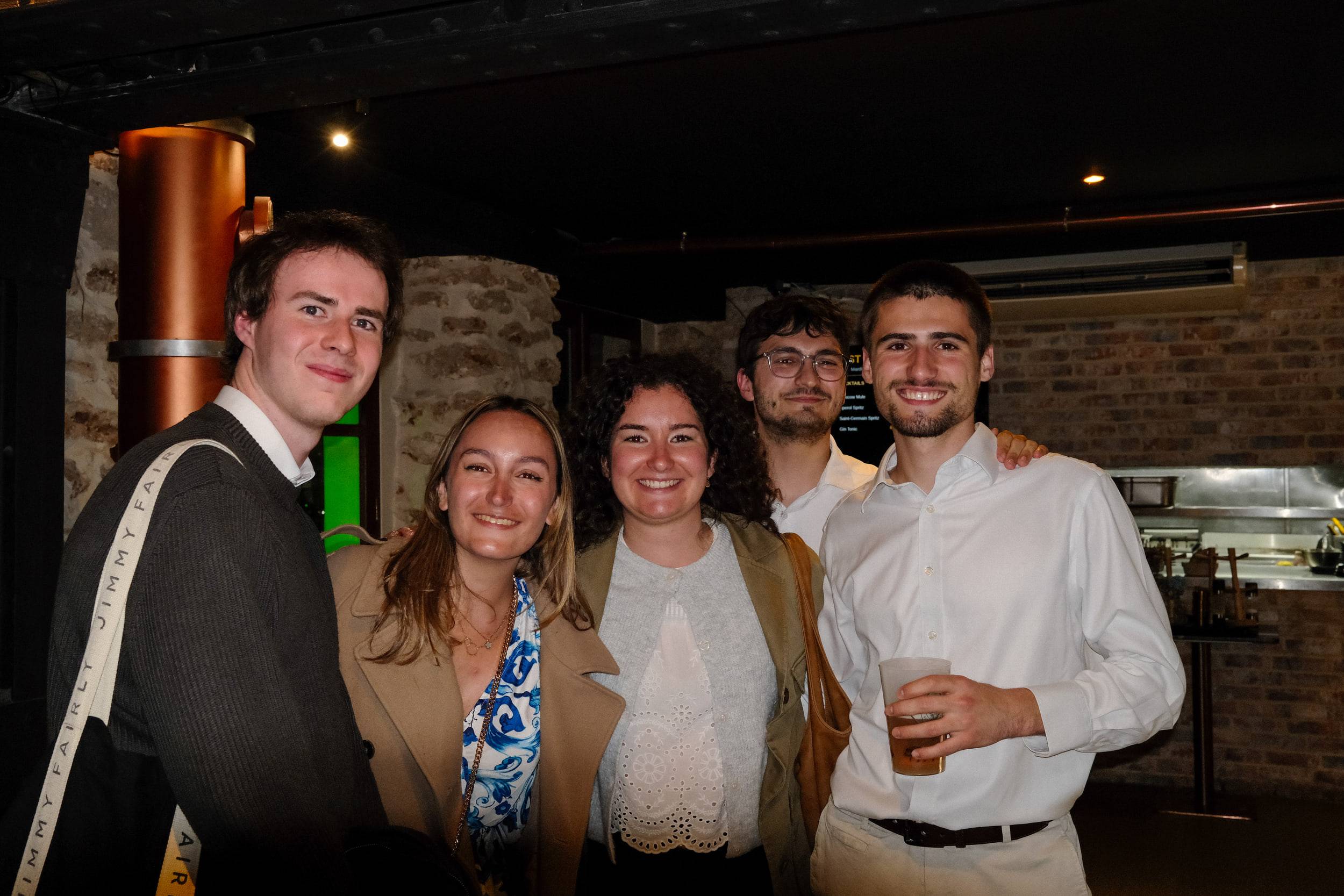Cinq étudiants posent près du comptoir, l'un d'eux tenant son gobelet devant lui.