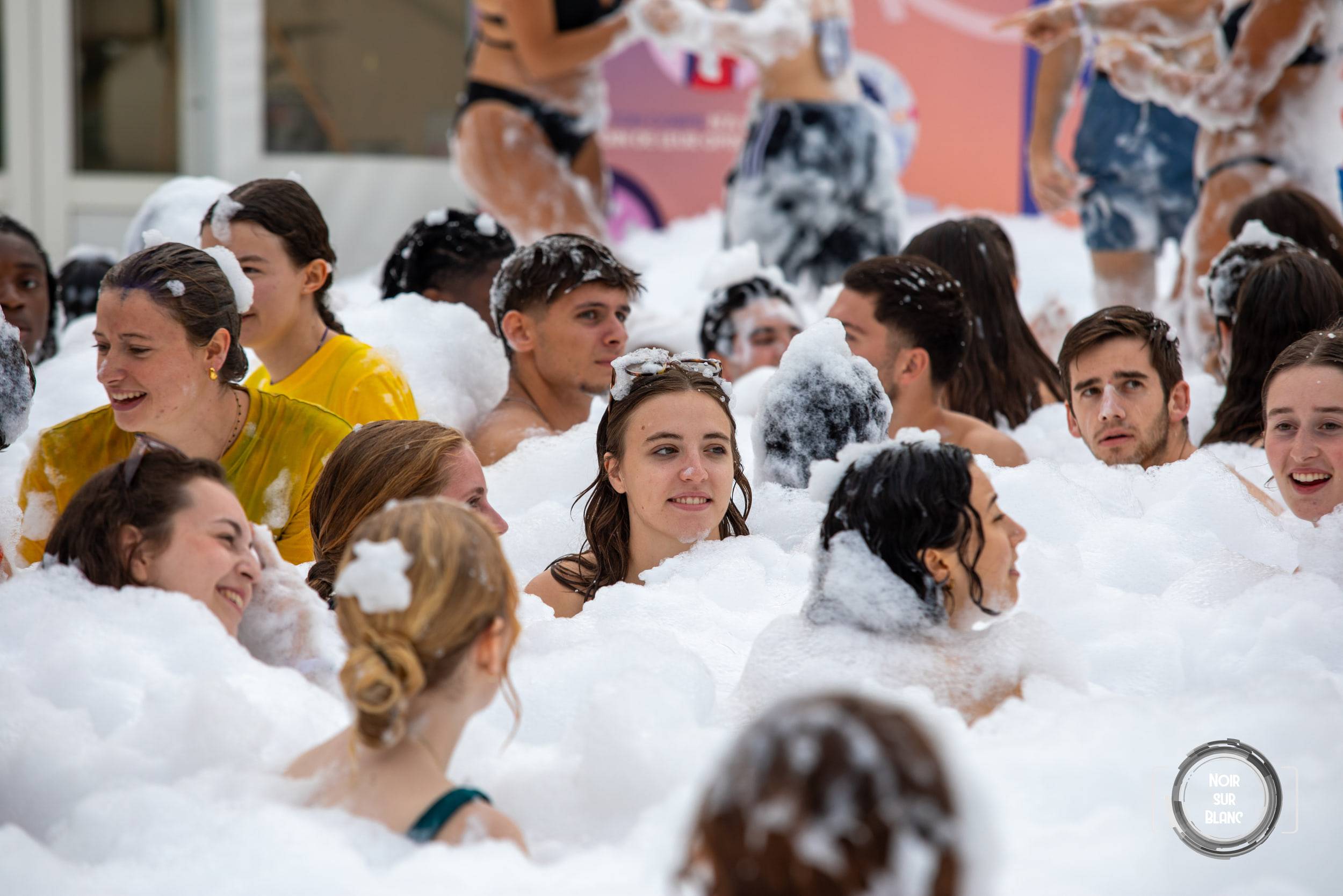 Une vingtaine de visages émergent d'une étendue de mousse blanche qui leur monte jusqu'au menton, certains riant, d'autres fixant l'objectif.